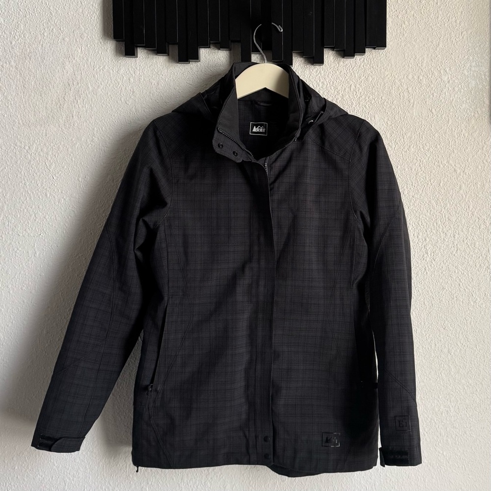 REl Elements
E1 rain jacket in a black and gray plaid pattern.